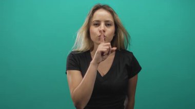 Deniz mavisi stüdyosunda parmakları dudaklarına değen bir kadın, sessiz sedasız hareket eden sarışın genç bir denek..