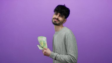 Canlı mor bir arka planda Rus rublesi tutan adam, kendine güvenen bir gülümsemeyle zenginlik ve ekonomik konsept sergiliyor..