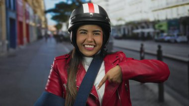 Kasklı ve askı sırıtan genç bir Latin kadın kalabalık bir caddeyi göstererek yaralanmasına rağmen kentsel ve aktif yaşam tarzını öneriyor..