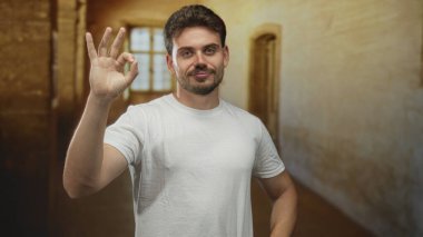 Bir adam eski bir bina koridorunda el işareti yapıyor, kameraya dönük şekilde, güven onayı.