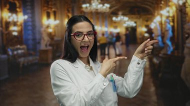 Müzede, cebinde kalemlerle üniforma giyen genç İspanyol bilim kadını gülümsüyor ve süslü ışıkların altında evi işaret ediyor..