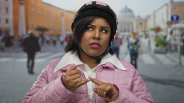 Pembe ceketli ve kasklı Latin kadın Vatikan caddesinde parmaklarıyla sayıyor..