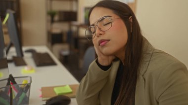 Ofisteki masasında gözleri kapalı dinlenen bir kadın gözlük takıyor. İş ortamında yorgunluk belirtileri gösteriyor..