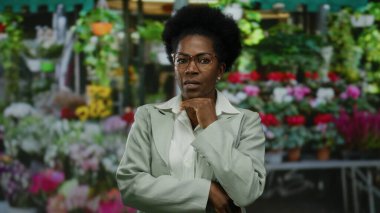 Renkli bir açık hava çiçekçisinin arka planında kendine güveni tam bir kadın şık gözlük takıyor ve hayat dolu bitkiler ve çiçeklerle çevrili..