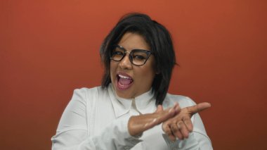 Kendine güveni tam ve gözlüklü bir kadın neşeli bir ifadeyle canlı kırmızı bir arka plana karşı para hareketi yapıyor..