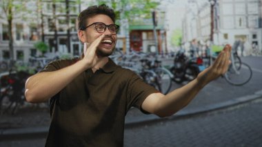 Erkek kıt kanaat geçiniyor diğer elini göğsüne koyuyor Amsterdam caddesinde; dost canlısı sevinç selamlaması.