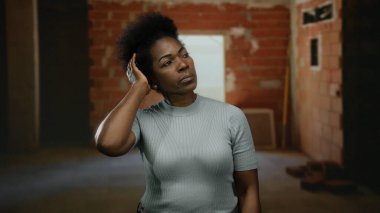 Tamamlanmamış bir inşaat sahasında üzerinde günlük giysiler ve odaklanmış bir ifadeyle şehir ortamında derin düşüncelere sahip bir kadın..