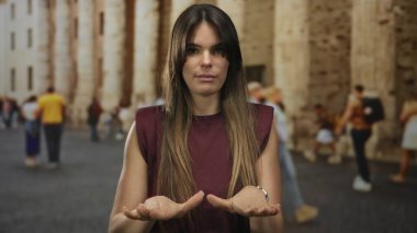 Şehir sokaklarında sakinlik için el kol hareketi yapan, bulanık kalabalığın ve tarihi mimarinin ortasında İspanyol genç bir kadını gösteren bir kadın..