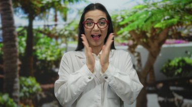 Genç İspanyol bilim kadını üniformalı neşeli bir şekilde arka planda yemyeşil bir yeşil alan olan canlı bir park ortamında heyecanını ifade ediyor..