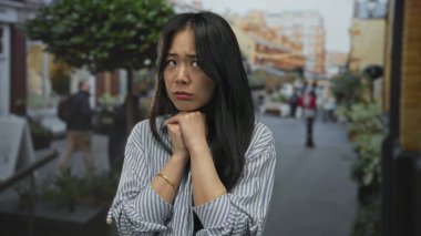 Kalabalık bir şehir caddesinde gülümseyen kadın, bulanık şehir manzarasıyla çevrili, yumuşak ışık altında kendine güvenen bir ifade sergiliyor..