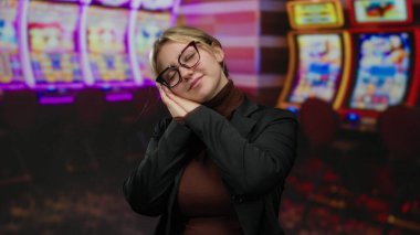 Kumarhanede arka planda kumar makineleri olan bir kadın. Parlayan ışıklar ve canlı ekranların arasında rahat bir duruş sergiliyor..