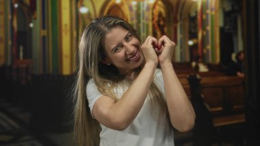 Kadın, tarihi kilisenin parlak iç mekanında elleri sıcacık gülümseyen yüzü ile kalp şekli oluşturur; dini bağlılık.