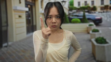 Kadın sokakta canlı bir şehirde kararlı bir ifade sergiliyor, kendine güveni somutlaştırıyor ve hareketli bir şehir ortamında odaklanıyor..