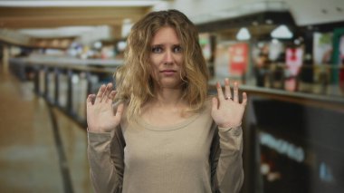 Bir alışveriş merkezine girmeyi reddeden bir kadın el ele tutuşuyor ve genç bir alışverişçi kapalı bir alışveriş ortamında hoşnutsuzluk jesti yapıyor..