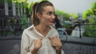 Kanal kenarındaki kaldırım taşı sokağında göğsü işaret eden İspanyol kadın. Şaşırtıcı bir şekilde kendini beğenmişlik..