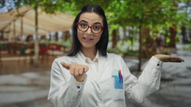 İspanyol kadın bilim adamı canlı ağaçlar ve şık bir üniformayla bir sokak sahnesinde doğal çevrede profesyonel ama yaklaşılabilir bir davranış sergiliyor..