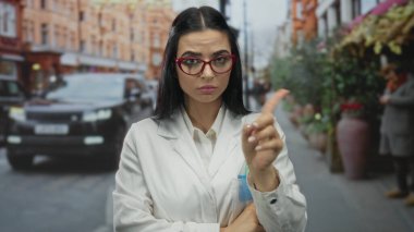 Kırmızı gözlüklü genç İspanyol bilim kadını şehir merkezinde yayalar geçerken kalabalık caddelerde arabalarla ve binalarla çevrili dışarıda dolaşmıyor.