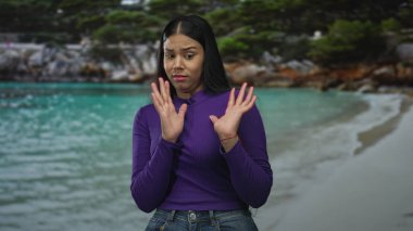 Kadın, turkuaz kıyı şeridinin yükseltilmiş el hareketlerini canlı güneş ışığı altında kayalık orman zeminiyle havada tutuyor..