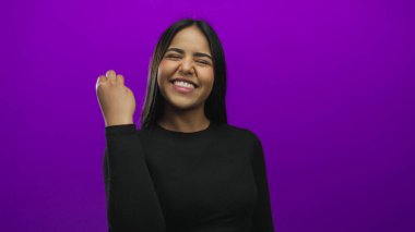 Hisse senedi görüntüsünde, mor arka planda izole edilmiş genç Latin Latin kimliğini vurgulayan, el kaldırılmış şef öpücüğü veren bir kadın yer alıyor..