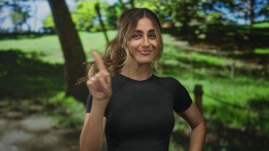 Sarışın kadın, güneş ışığı altındaki ormanda el ele tutuşarak saçların hafifçe eserken, kendine güvenen bir oyuncu olduğunu gösteriyor..