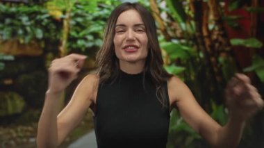 Çıplak kollarıyla kaya boynuzları yapan ve dilini yemyeşil orman ortamında uzatan kadın, heyecan..