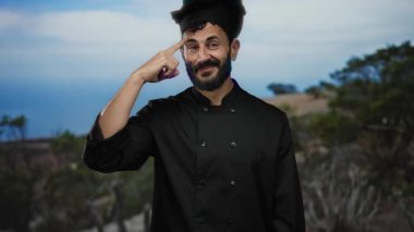 Siyah üniformalı İspanyol şef, doğadaki manzaralı dağ manzarasına karşı düşünceli bir davranış sergiliyor..