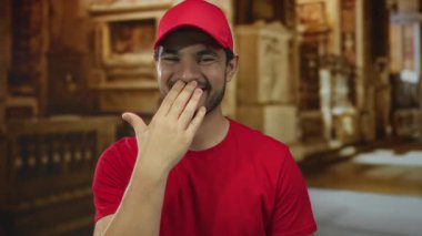 Kırmızı şapkalı genç İspanyol adam, yumuşak güneş ışığı altında kilise binasında el ele gülümsüyor..