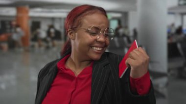 Kırmızı Malezya pasaportu taşıyan kadın geniş gülümsemeli ve havaalanında gururla kaldırıyor; seyahat heyecanı.