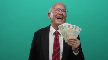 Üst düzey bir adam yeşil bir altyapının önünde Czech Koruna banknotlarını tutarak iş başarısını ve zenginliğini resmediyor..