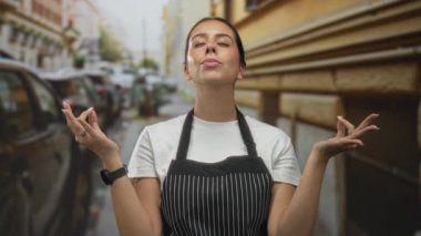 Meditasyonda elleri ve gözleri kalabalık bir caddede kapalı çizgili önlük giyen bir kadın..