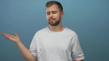 Avuç içleriyle omuz silken beyaz genç bir adam stüdyoda mavi arka plana karşı görünür eller; belirsizlik.