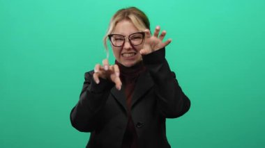 Yeşil arka planda komik jestleri olan siyah elbiseli kadın etkileyici bir kişilik ve oyuncu bir mizaç sergiliyor..