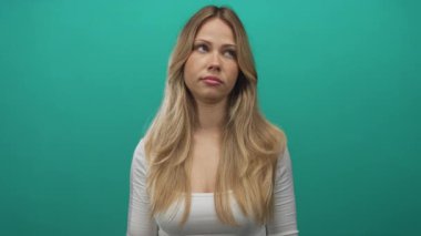 Sarışın kadın, parlak yeşil bir fotoğraf stüdyosunda çıplak elleriyle alkışlar; alaycılık..