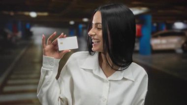 Otoparkta elinde beyaz gömlekle gülümseyen genç bir İspanyol kadın..