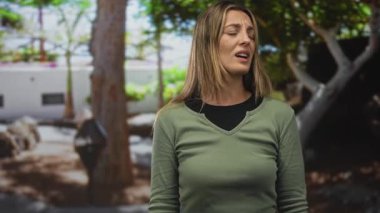 Ağaçların ve bina duvarlarının yakınındaki ormanda göz kapama ve yumruk yumruğa boğuşan kadın..