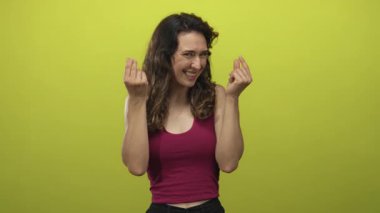 İspanyol kadın yeşil stüdyo duvarına karşı parmaklarıyla para hareketi yapar; şakacı zenginlik coşku arzusu.