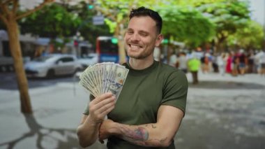 Kentsel sokak gösterilerinde Amerikan doları tutan genç adam güneşli, açık şehir ortamında Birleşik Devletler banknotları.