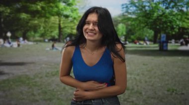 Ormanda karın ağrısı için karın üstü uzanan kadın gergin bir duruş ve acı dolu bir ifade sergiliyor..