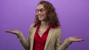 Kırmızı gözlüklü ve spor ceketli, elleri mor arka planda gülümseyen, mutluluk ve iletişimi ifade eden bir kadın..