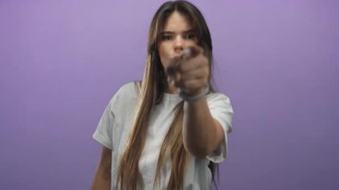 Mor bir arka plana karşı el hareketleriyle öfke ifade eden bir kadın izole bir ortamda yüz ifadeleri yoluyla duygu ve hayal kırıklığı sergiliyor..