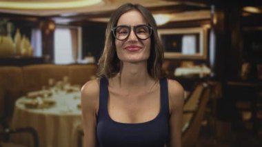 Lokantanın içinde yemek masaları ve sıcak aydınlatma ile kollarını açmış gülümseyen kadın, konukseverlik sevinci..