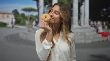 Kadınlar tarihi meydanda yanaklarına jöleli donut tutarken beyaz gömlek giyiyorlar; keyif düşkünlüğü hoşnutluğu.