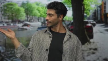 Genç Hispanik adam sokakta açık avuç içinin dışa dönük hareketlerine bakar; bağlantı sakinliği iç gözlem.