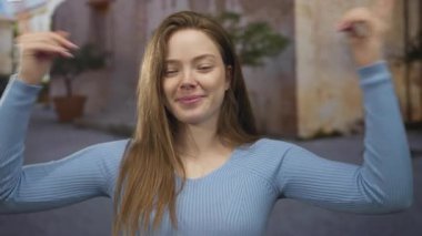 Uzun saçlı ve mavi kazaklı kadın gülümsüyor. Güneşli eski şehrin kaldırım taşı sokağında burun buruna. Eğlenceli bir an..