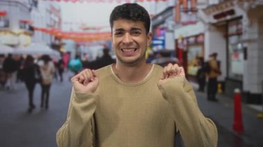 Genç İspanyol erkek sokak ortasında halka açık alanda dikilirken adam ellerini kaldırıyor..