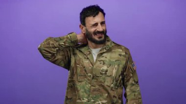 Askeri üniformalı İspanyol bir adam. Mor arka planda duran sakallı. Boynuna dokunarak rahatsızlığını gösteriyor..