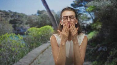 Gözlüklü genç bir kadın öpücük yolundaki ellerden dudaklara, sevgi dolu bir sevinç..