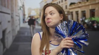 Kafkasyalı genç amigo kız mavi ponponu tutuyor ve şehir caddesinde gözlerini yuvarlıyor. Hayal kırıklığı..