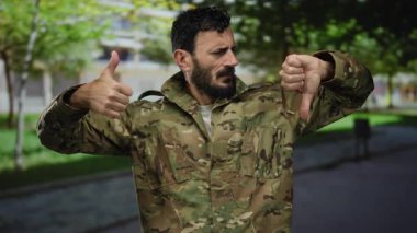 Üniformalı İspanyol askeri bir adam açık havada baş parmak işareti yapıyor, ilginç bir açık hava ortamında farklı görüşleri yansıtıyor..