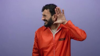 Sakallı, hapishane tulumu giymiş İspanyol bir adam mor arka plandan dinliyordu..